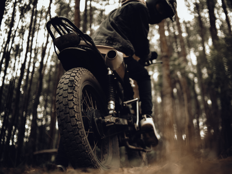 The guy is sitting on a dirty bike in the forest