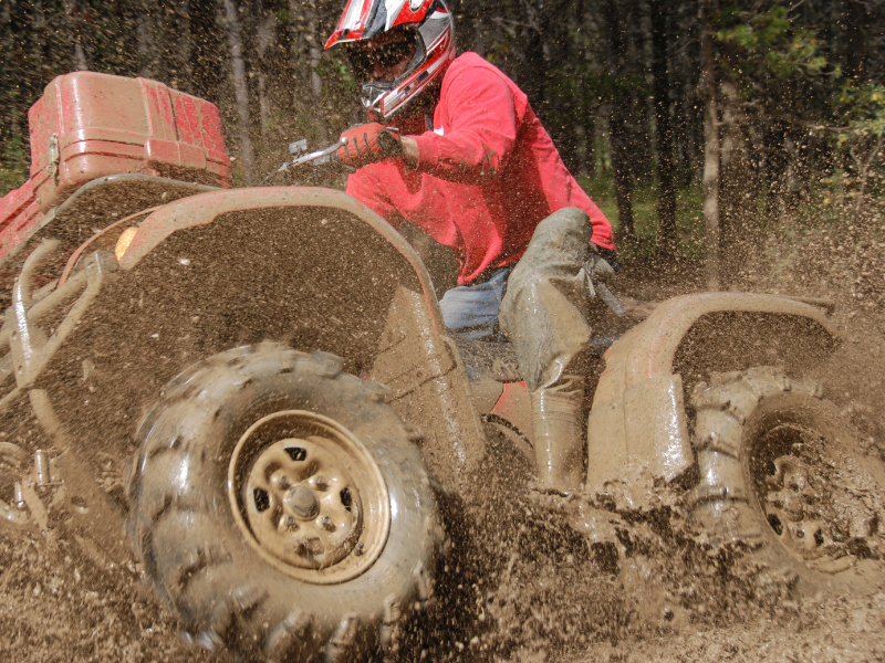 A man on an ATV boot in the mud