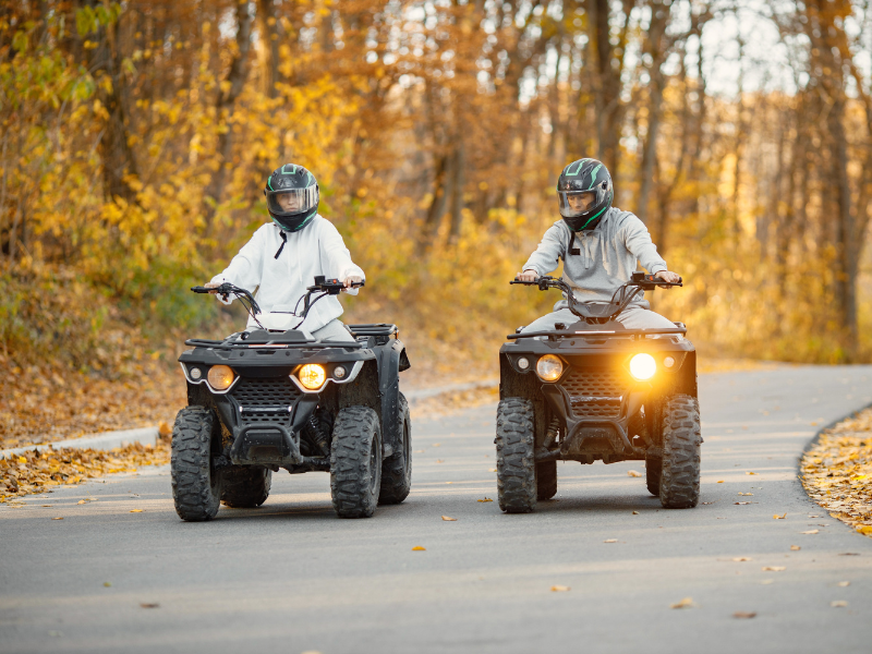 Two people riding ATVs on the road
